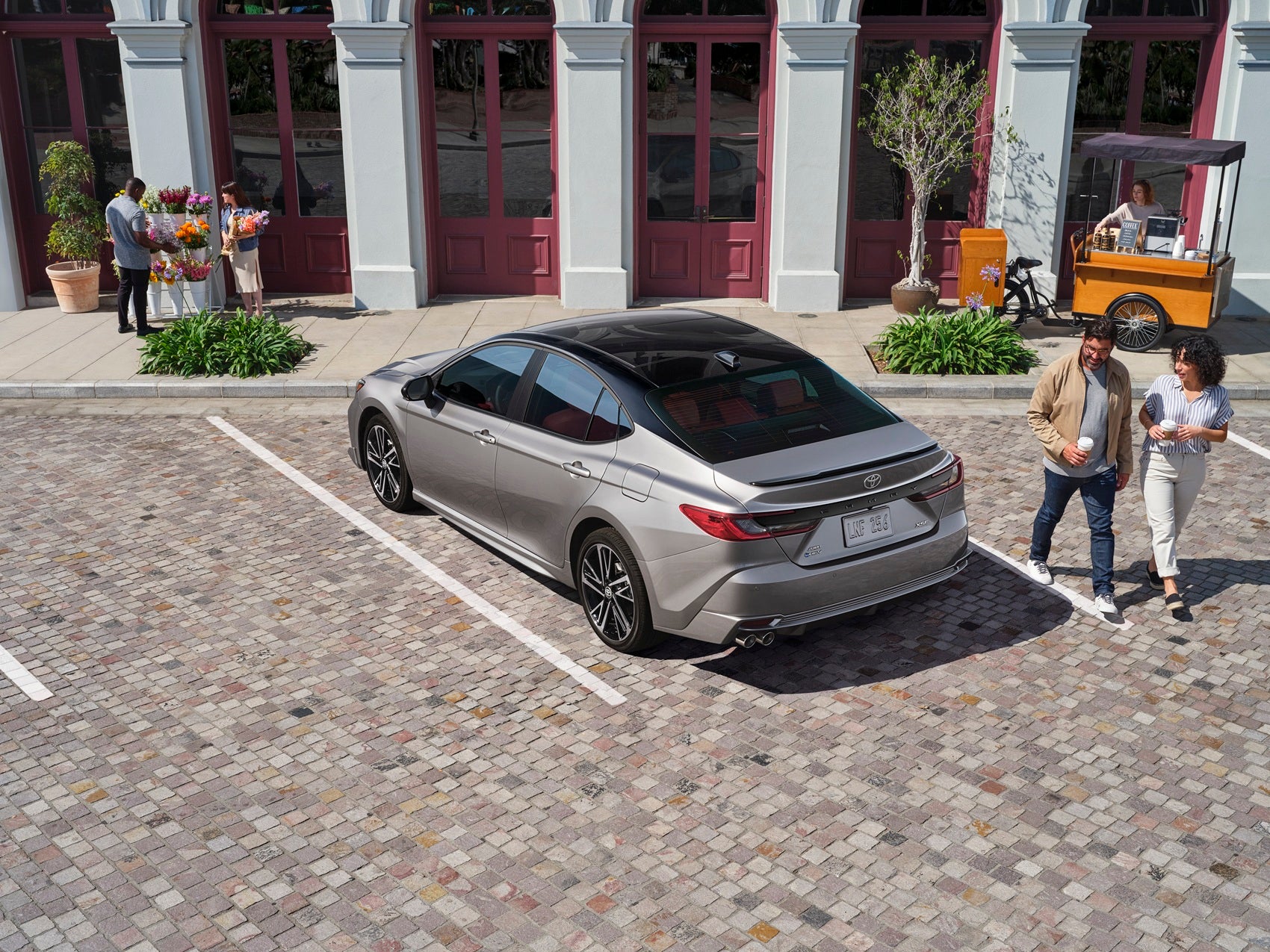 Toyota Camry exterior rear view with couple walking on urban sidewalk